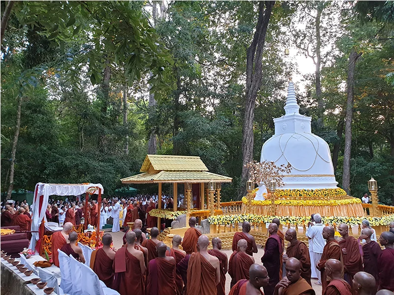 Monks gathered beside a white stupa in the forest at Na Uyana